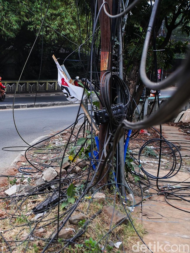 Semrawut! Kabel Fiber Optik Bergelantungan di Jalan Raya Cirendeu
