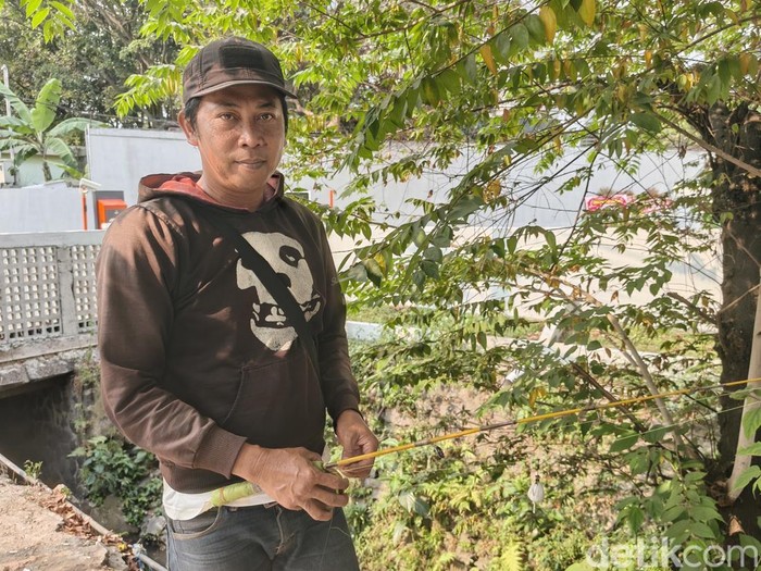 Dede Sobat (49), pedagang asal Bandung yang memilih menghabiskan waktu sebelum berdagang dengan memancing ikan.