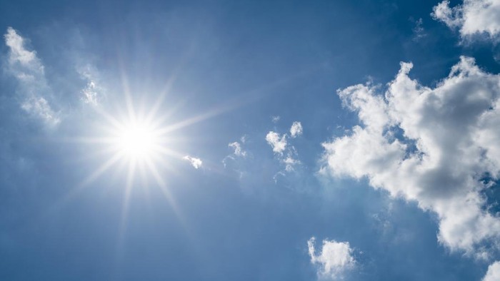 Sun on blue sky with clouds.