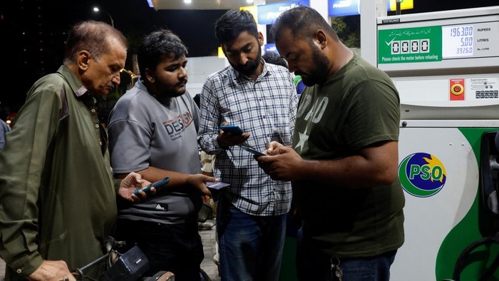 Pakistan Berlakukan Subsidi BBM untuk Kendaraan Kecil A worker checks customers' mobile phones for a code before refuelling their vehicles at a petrol station following the rollout of a fuel relief scheme, which provides a fuel subsidy for eligible motorcycles, rickshaws and vehicles with engines of up to 800cc, in Karachi, Pakistan, September 17, 2026. REUTERS/Akhtar Soomro