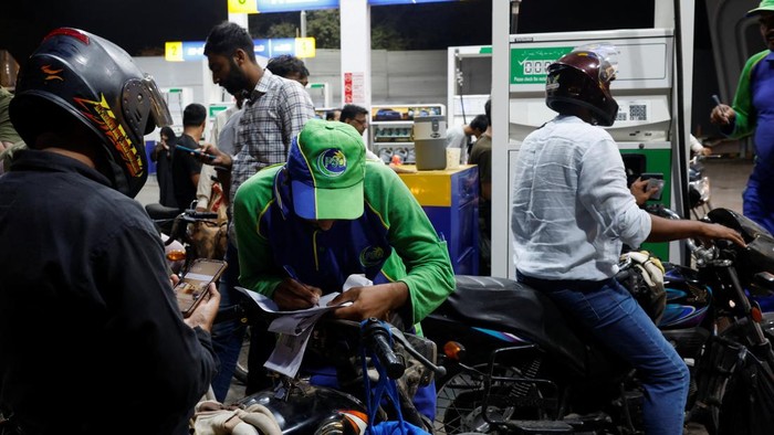 Pakistan Berlakukan Subsidi BBM untuk Kendaraan Kecil A worker checks customers' mobile phones for a code before refuelling their vehicles at a petrol station following the rollout of a fuel relief scheme, which provides a fuel subsidy for eligible motorcycles, rickshaws and vehicles with engines of up to 800cc, in Karachi, Pakistan, September 17, 2026. REUTERS/Akhtar Soomro
