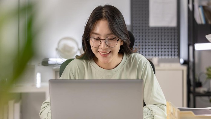 Student laptop online learning woman home office eyeglasses young adult smiling technology computer
