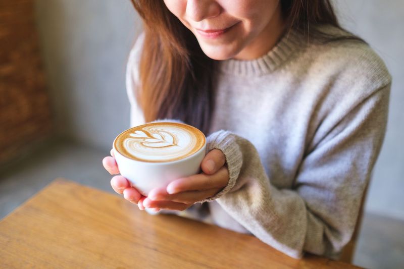 Closeup image of a woman holding a cup of hot latte coffee