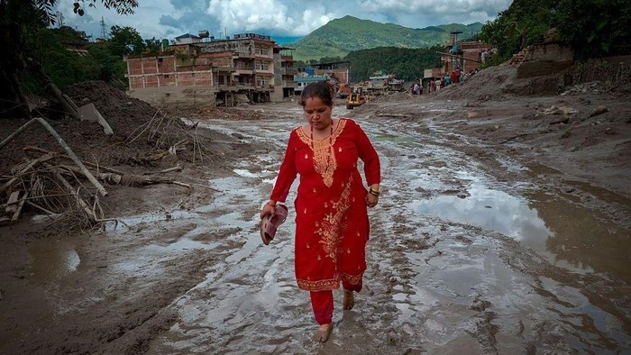 Seorang warga berjalan di sepanjang jalan berlumpur setelah banjir bandang pada 27 Agustus 2026 di Trishuli, Nepal (Getty Images)