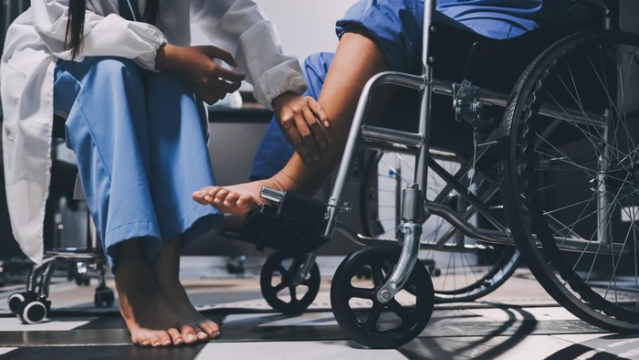 Physiotherapist nurse doing physiotherapy to rehabilitate leg of elderly female patient.