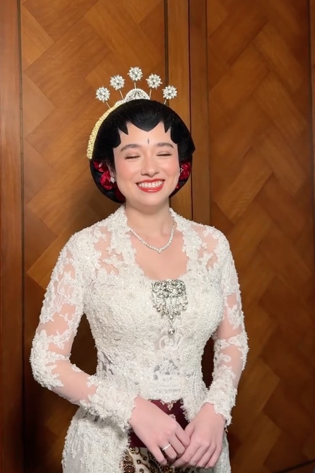 Amanda diketahui mengenakan kebaya rancangan Didiet Maulana. Kebaya putih dengan potongan yang mengikuti bentuk tubuh itu dihiasi bordir motif bunga, payet, serta embellishment berkilau yang memberikan kesan mewah. Detail floral tiga dimensi juga terlihat menyebar dari bagian bahu hingga lengan. Foto: Instagram/@leoafandi_