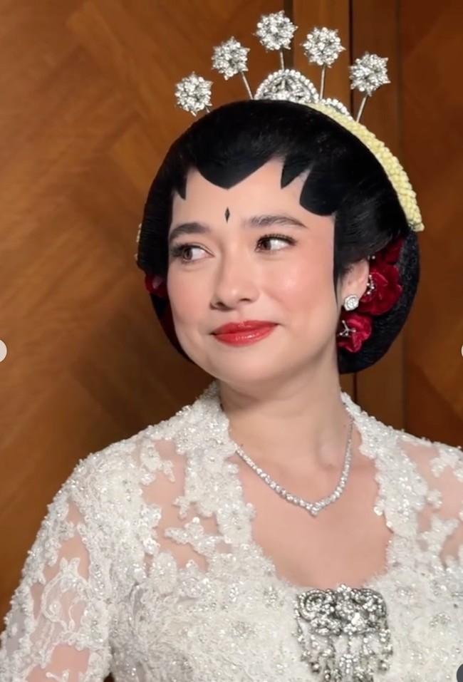Di bagian tengah dada terdapat bros besar bernuansa silver yang dihiasi susunan kristal. Bentuknya menyerupai rangkaian bunga atau ornamen permata yang menjuntai ke bawah.  Foto: Instagram/@leoafandi_