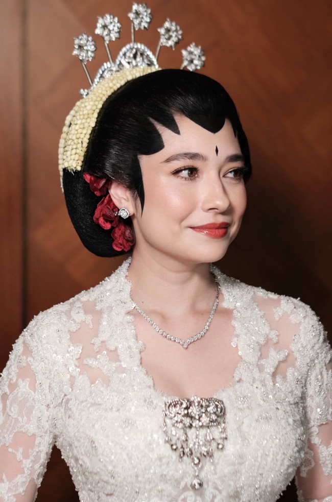 Sementara untuk riasan wajah, Amanda mempercayakan pada MUA Leo Afandi. Riasannya dibuat dengan konsep soft glam yang tetap terlihat natural. Complexion tampak halus, bersih, dan sedikit glowing. Mata dipertegas dengan eyeshadow cokelat lembut, eyeliner tipis, serta bulu mata yang lentik. Blush bernuansa pink-peach memberikan rona segar pada pipi, sementara bibir menggunakan warna merah bata atau merah kecokelatan dengan sedikit efek glossy. Foto: Instagram/@leoafandi_