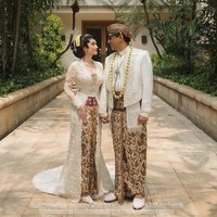 Amanda Rigby dan Andre Taulany tampil menjadi pengantin Jawa dalam balutan kebaya dan beskap putih yang dipadukan kain batik palet putih-cokelat. Sentuhan stagen warna merah marun memberikan aksen kontras pada penampilan Amanda. Foto: Dok. Instagram Didiet Maulana, Amoretorganizer