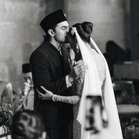 Sementara itu, Givina tampil dalam gaun pengantin putih dengan siluet fitted. Busananya memiliki detail transparan pada bagian lengan yang dihiasi motif floral serta embellishment berkilau. Bagian bodice hingga rok dipenuhi detail payet dan kristal yang membentuk pola memanjang. Siluetnya mengikuti bentuk tubuh sebelum melebar di bagian bawah, memberikan kesan seperti mermaid gown.  Foto: Instagram @caesarmario