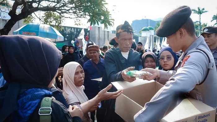 Personel polisi turun membagikan roti dan air mineral di tengah aksi massa di depan DPR, Senin (21/9/2026) siang tadi.