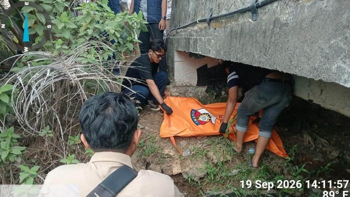 Polisi saat mengevakuasi jasad bayi yang ditemukan dalam selokan