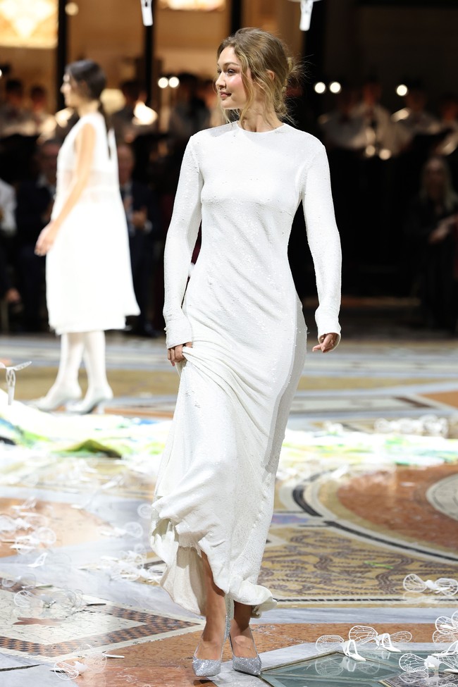 Tak hanya satu look, Gigi kembali tampil di runway dengan penampilan keduanya, mengenakan gaun putih. Foto: Getty Images for Vogue/Daniele Venturelli