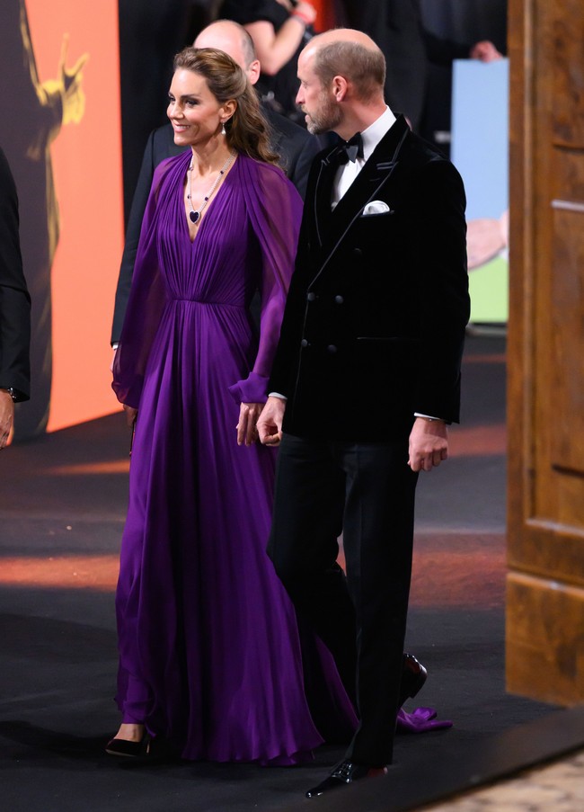 Kate mengenakan gaun berwarna royal purple dengan detail lipit yang elegan. Busana dipercantik detail semi-transparan yang memberikan kesan anggun, sementara rambut yang ditata terurai dengan gelombang lembut, melengkapi penampilannya pada Selasa (22/9/2026) malam itu. Foto: WireImage/Karwai Tang