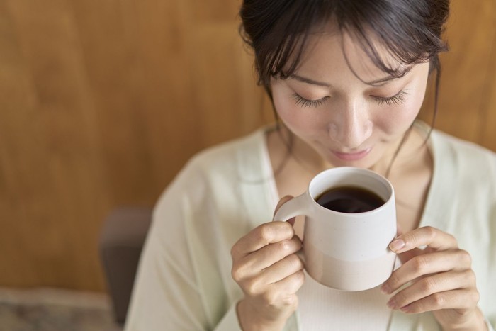 Young woman relaxing on sofa with hot drink