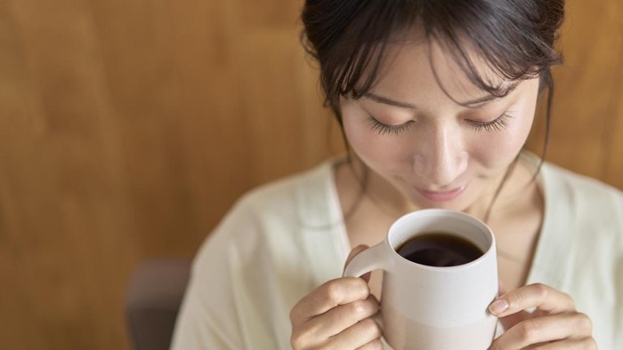 Young woman relaxing on sofa with hot drink
