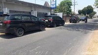 Dalam proses penggeledahan, sejumlah mobil berpelat L dan W tampak terparkir di depan. Proses ini mendapat pengawalan dari anggota Brimob bersenjata lengkap.