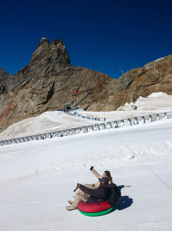 A tourist enjoys snow tubing on a glacier amid climate change, at the Jungfraujoch which has an elevation of 3,454 metres above sea level (11,332 feet), near Grindelwald, Switzerland, September 23, 2026, REUTERS/Denis Balibouse