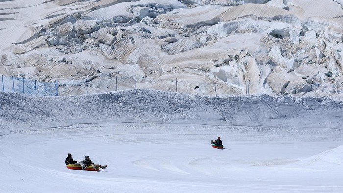 A tourist enjoys snow tubing on a glacier amid climate change, at the Jungfraujoch which has an elevation of 3,454 metres above sea level (11,332 feet), near Grindelwald, Switzerland, September 23, 2026, REUTERS/Denis Balibouse