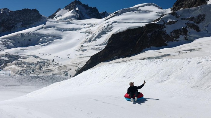 A tourist enjoys snow tubing on a glacier amid climate change, at the Jungfraujoch which has an elevation of 3,454 metres above sea level (11,332 feet), near Grindelwald, Switzerland, September 23, 2026, REUTERS/Denis Balibouse