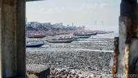 Sejumlah perahu nelayan berdasar di kawasan Pantai Kenjeran, Surabaya, Jumat (25/9/2026). Hamparan pesisir yang terbuka membuat tumpukan sampah dan bebatuan terlihat jelas.