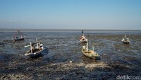 Sejumlah perahu nelayan tampak berada di atas kawasan pantai yang mengering saat air laut surut di Pantai Kenjeran, Surabaya, Jumat (25/9/2026).