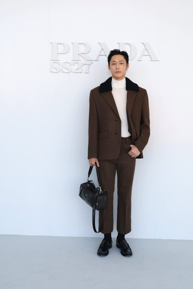 Kontras dengan Jaehyun NCT, Lee Do Hyun memakai atasan berkerah tinggi berwarna putih. Dilengkapi setelan jas coklat dengan detail kerah berbulu. Bahkan mendobrak standar berpakaian pria dengan koleksi hand bag wanita Prada. Foto: Dok. X