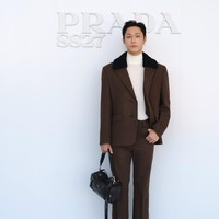 Kontras dengan Jaehyun NCT, Lee Do Hyun memakai atasan berkerah tinggi berwarna putih. Dilengkapi setelan jas coklat dengan detail kerah berbulu. Bahkan mendobrak standar berpakaian pria dengan koleksi hand bag wanita Prada. Foto: Dok. X