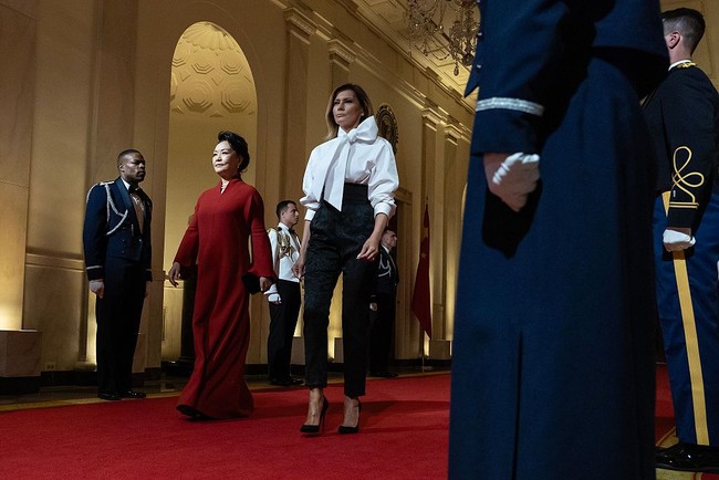 Sementara itu, Peng Liyuan memilih gaun bersiluet kaftan berwarna merah yang solid, dipadu clutch hitam dengan sentuhan buckle emas, yang menyempurnakan tampilan klasiknya. Di Negeri Tirai Bambu, merah juga merepresentasikan kemakmuran. Namun di sisi lain, merah dalam perpolitikan AS selalu terasosiasi dengan  Partai Republik yang menaungi Trump. (Foto: Kevin Dietsch/Getty Images)