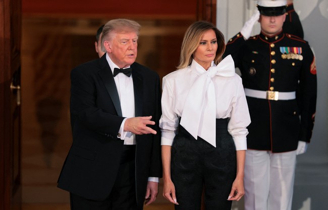 Melania memadukan bawahan tersebut dengan atasan blus putih dari Yves Saint Laurent. Bagian kerah dihiasi pita besar yang dramatis. Tidak ketinggalan sepasang heels hitam Christian Louboutin untuk menyempurnakan gayanya. (Foto: REUTERS/Kylie Cooper)