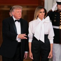 Melania memadukan bawahan tersebut dengan atasan blus putih dari Yves Saint Laurent. Bagian kerah dihiasi pita besar yang dramatis. Tidak ketinggalan sepasang heels hitam Christian Louboutin untuk menyempurnakan gayanya. (Foto: REUTERS/Kylie Cooper)