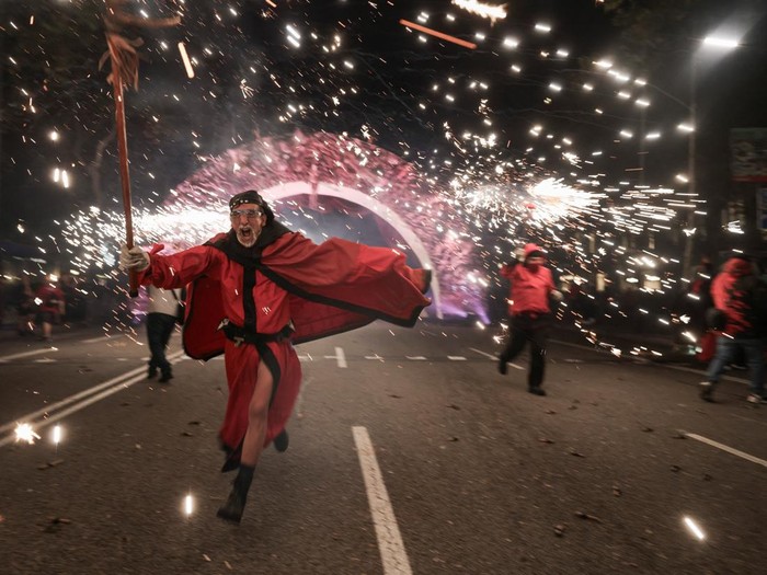 Valentyna, 37, from Russia and her friend Maria, 42, from Ukraine react as performers dressed as devils hold sticks spewing fire sparks during the traditional 