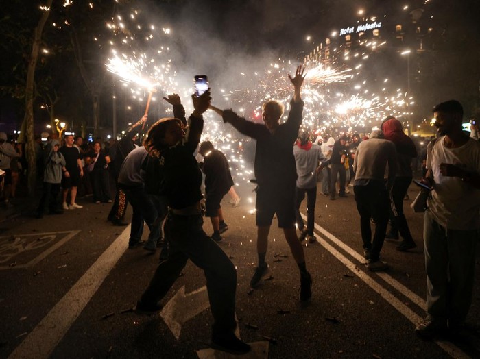 Valentyna, 37, from Russia and her friend Maria, 42, from Ukraine react as performers dressed as devils hold sticks spewing fire sparks during the traditional 
