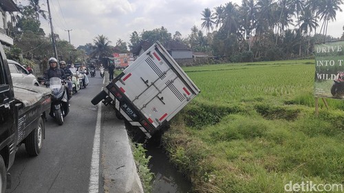 Kondisi mobil boks terjepit di parit usai menabrak pemotor hingga terpental di kebun waega di Desa Bongkasa, Badung, Senin (28/9/2026). (Agus Eka)