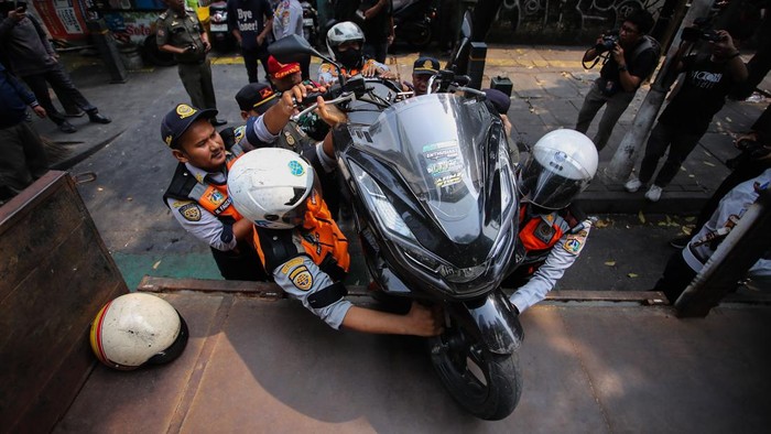 Petugas gabungan mengangkut sepeda motor yang parkir di bahu jalan ke atas truk di Jalan Senopati, Jakarta Selatan, Senin (28/9/2026).