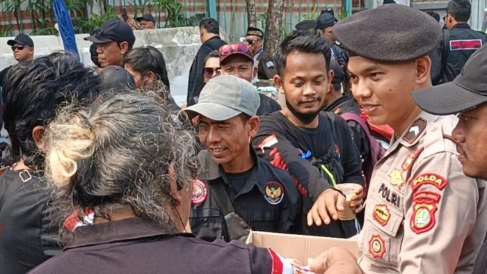 Personel Polda Metro Jaya membagikan air mineral dan roti ke massa aksi di Silang Monas, Jakarta Pusat, Senin (28/9/2026).