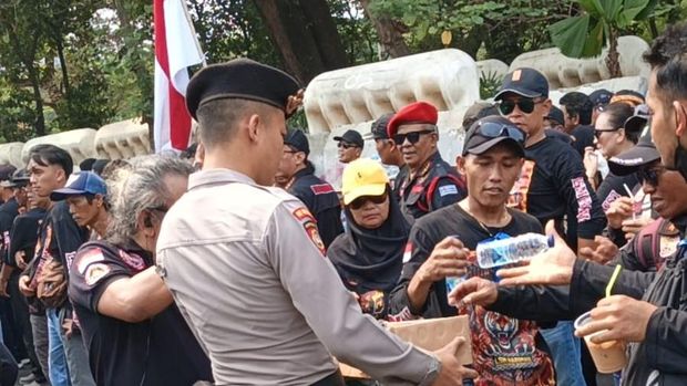 Personel Polda Metro Jaya membagikan air mineral dan roti ke massa aksi di Silang Monas, Jakarta Pusat, Senin (28/9/2026).