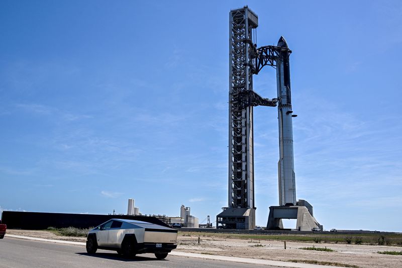 A Tesla Cybertruck drives past pad 2, where Starship 41 sits atop Super Heavy v3 Booster 21 at SpaceX launch complex, as preparations continue for the 14th test flight in Starbase, Texas, US, September 27, 2026. The mission is expected to send the vehicle into orbit for the first time and deploy 26 Starlink V3 satellites. REUTERS/Steve Nesius ,
