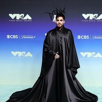 Penyanyi Adam Lambert hadir di VMA 2026 untuk tampil dalam tribute bagi George Michael dengan mengenakan busana custom Charles de Vilmorin. Jubah hitam bergaya gothic dengan lengan mengembang dipadukan dengan headpiece bertuliskan Adam’. Luarannya polos tanpa detail menarik membuat gaya Adam terasa membosankan.  Foto: Getty Images/Frazer Harrison