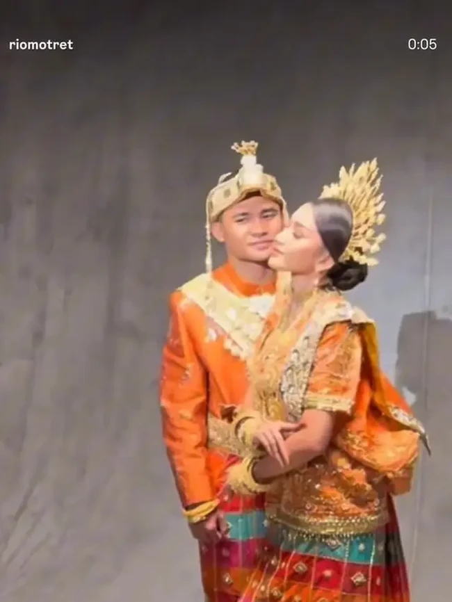 Asnawi dan Yuriska kompak dalam balutan busana adat yang didominasi warna oranye dihiasi motif dan ornamen berwarna emas. Penampilan keduanya makin lengkap dengan aksesori dan hiasan kepala yang juga berwarna emas. Foto: Instagram/@riomotret