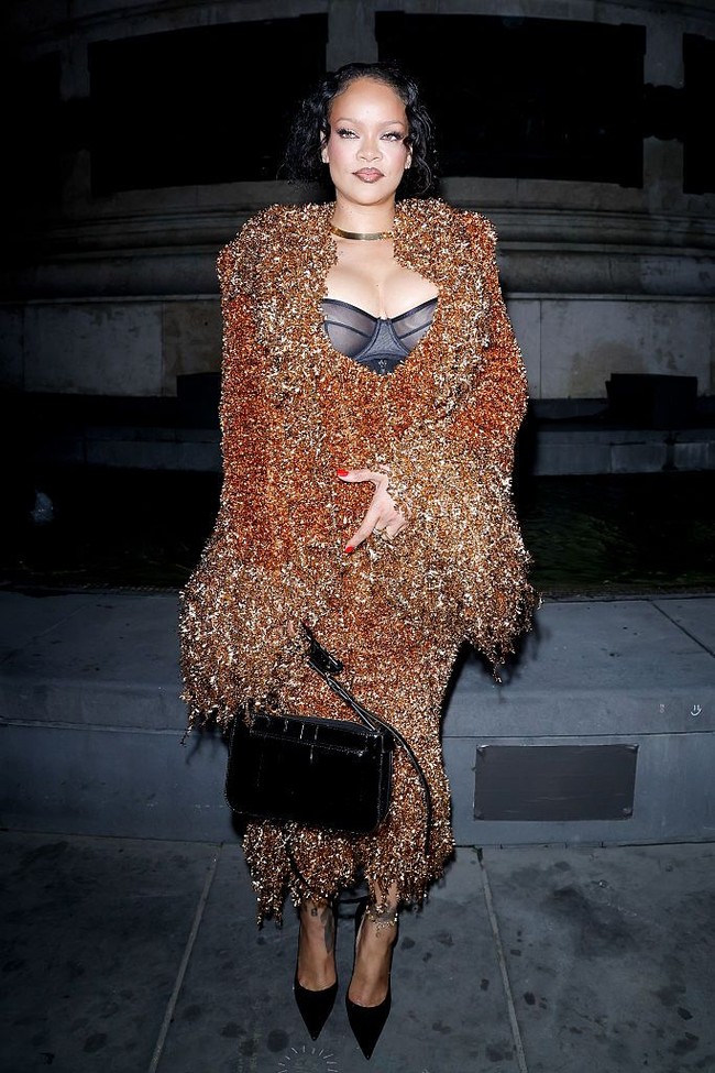 Rihanna mengenakan bra top hitam transparan di balik setelan tersebut, memancarkan aura seksi dan edgy, yang jadi ciri khas gayanya. Foto: WWD via Getty Images/WWD