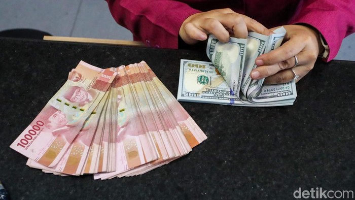 Petugas menghitung pecahan dolar AS dan rupiah di gerai penukaran mata uang asing VIP Money Changer, Jakarta, Selasa (29/9/2026).