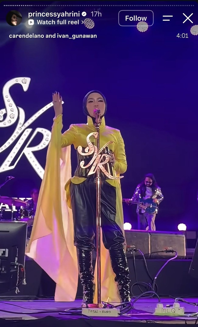 Syahrini diketahui mengenakan busana rancangan Ivan Gunawan. Ia mengenakan atasan berwarna kuning cerah dengan desain berkerah tinggi dan lengan panjang. Detail paling mencolok adalah kain kuning panjang menyerupa cape yang menjuntai dari sisi tubuh hingga menyentuh lantai. Foto: Instagram/@princessyahrini