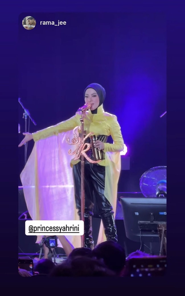 Bagian bawah menggunakan celana hitam dengan material yang terlihat seperti kulit atau vinyl. Permukaannya mengilap dan memiliki efek kerutan, memberikan kesan bold sekaligus modern pada keseluruhan penampilan. Foto: Instagram/@princessyahrini