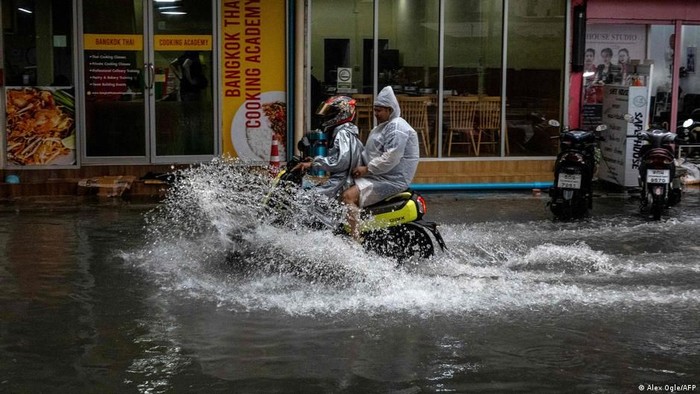 Para komuter mengendarai skuter menerobos genangan banjir di Bangkok, Thailand, setelah hujan deras mengguyur ibu kota selama beberapa hari dan menyebabkan banjir di sejumlah kawasan pada 25 September 2026 (Alex Ogle/AFP)