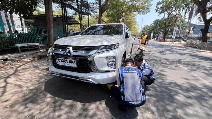 Dishub Makassar menggembok mobil parkir sembarangan di bahu jalan.