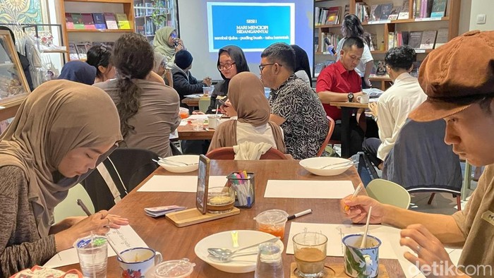 Dua peserta Merawat Ingatan dari Sepiring Resep Gerwani tengah menuliskan kesan setelah mencicipi tiga kudapan, Rabu (30/9/2026).