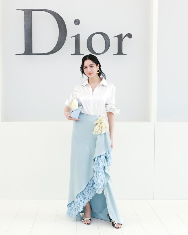 LingLing Kwong menghadirkan gaya feminin dengan pendekatan yang lebih modern. Bintang asal Thailand yang lahir di HongKong itu mengenakan rok satin biru pastel asimetris dari Dior Cruise 2027. Rok tersebut dipadukan dengan kemeja putih dan detail ruffle yang jatuh tidak simetris di salah satu sisi. Permainan warna pastel dan material satin membuat penampilannya terasa lembut, sementara potongan asimetris memberikan sentuhan kontemporer. (Foto: Dok. Dior)