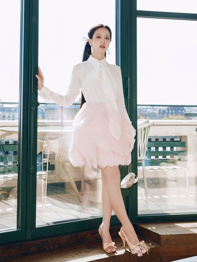 Blus putih dipadukan dengan rok mini warna baby pink. Lipatan dan susunan kain menciptakan volume bak kelopak bunga yang feminin sekaligus playful. Foto: Instagram/@sooyaaa__