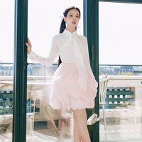 Blus putih dipadukan dengan rok mini warna baby pink. Lipatan dan susunan kain menciptakan volume bak kelopak bunga yang feminin sekaligus playful. Foto: Instagram/@sooyaaa__